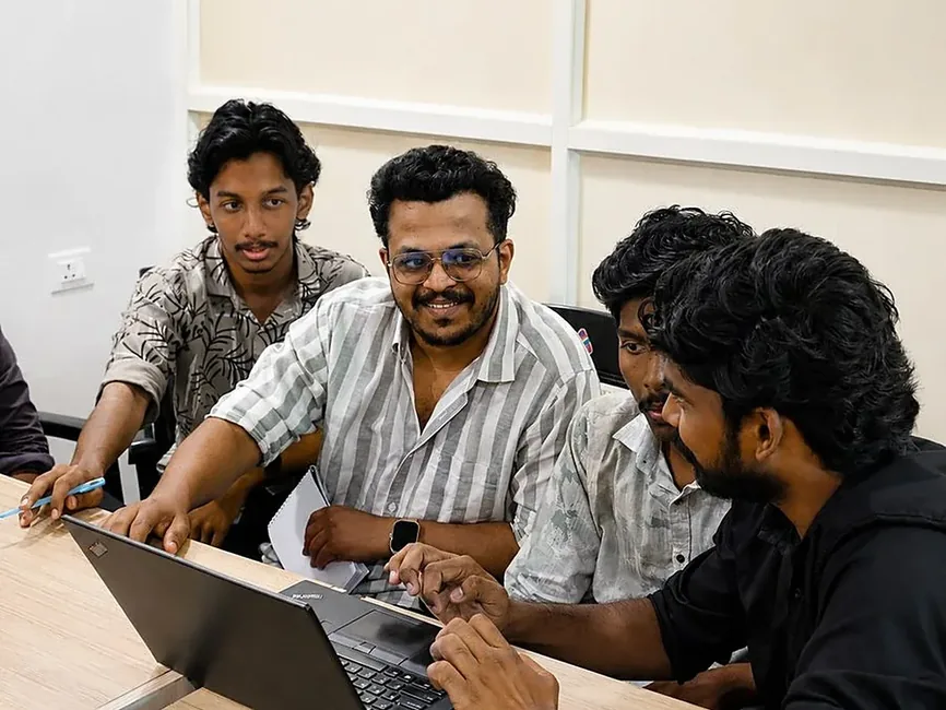 A trainer working through an exercise with learners at a laptop